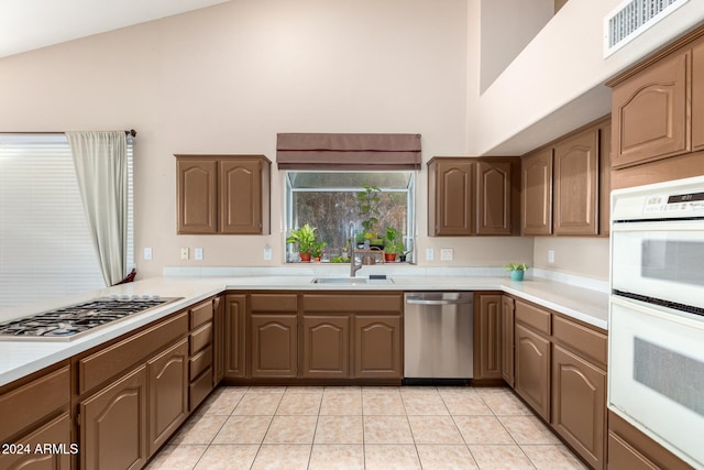 kitchen featuring sink, light tile patterned floors, high vaulted ceiling, and appliances with stainless steel finishes