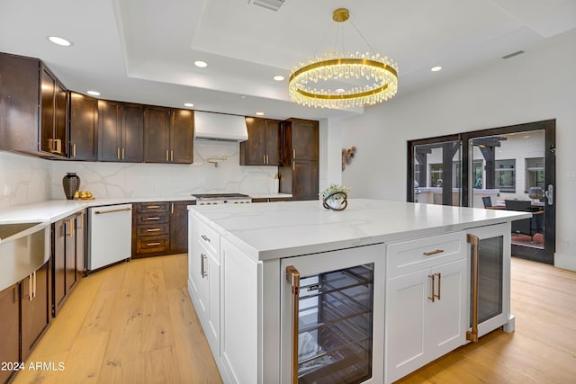 kitchen featuring light wood-style flooring, wall chimney exhaust hood, dishwasher, and beverage cooler