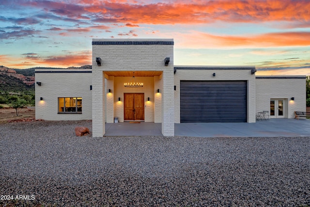 view of front facade featuring french doors, brick siding, concrete driveway, and an attached garage