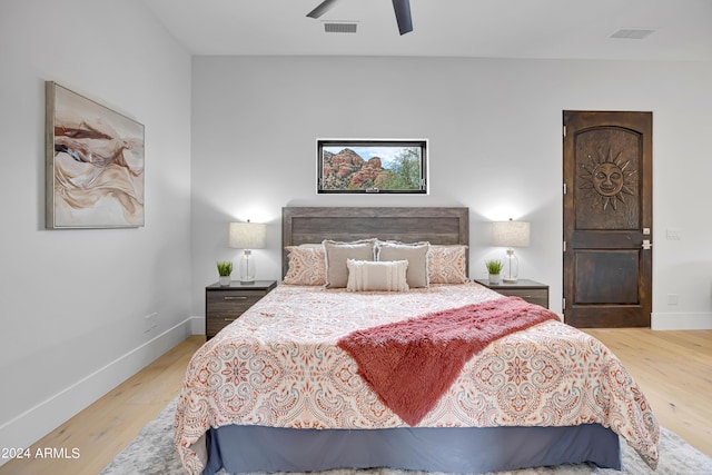 bedroom featuring visible vents, a ceiling fan, baseboards, and wood finished floors