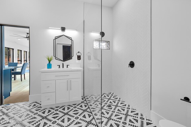 full bathroom with vanity, a ceiling fan, a tile shower, tile patterned floors, and toilet