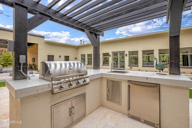 view of patio with an outdoor kitchen, a grill, a pergola, and a sink