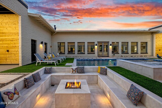 patio terrace at dusk with an outdoor pool and a fire pit