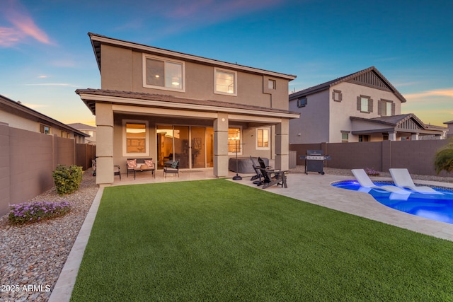 back house at dusk featuring a patio area, a yard, a fenced in pool, and an outdoor hangout area