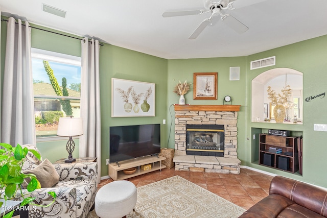 tiled living room with ceiling fan and a fireplace