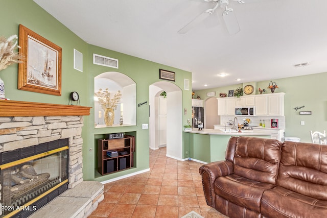 tiled living room with sink, ceiling fan, and a fireplace