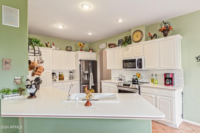 kitchen featuring stainless steel appliances, light tile patterned floors, tasteful backsplash, sink, and white cabinetry