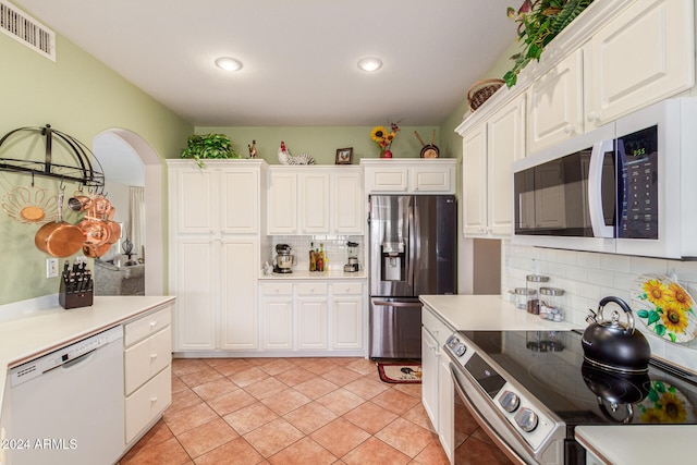 kitchen with tasteful backsplash, white cabinets, light tile patterned floors, and stainless steel appliances