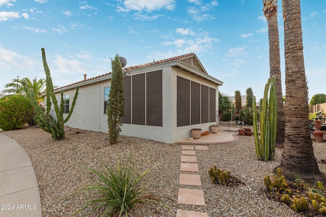 view of side of property featuring a sunroom and a patio area