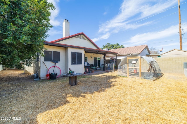 rear view of property featuring a fenced backyard, a chimney, a greenhouse, an outdoor structure, and a patio area