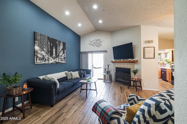 living area with lofted ceiling, a fireplace, visible vents, and wood finished floors