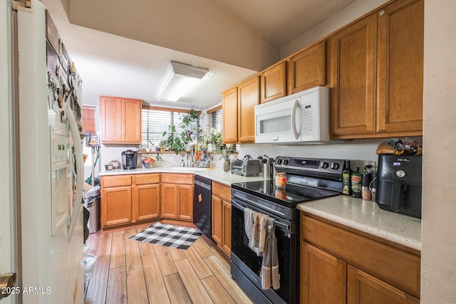 kitchen featuring black dishwasher, light countertops, white microwave, light wood-type flooring, and stainless steel electric range