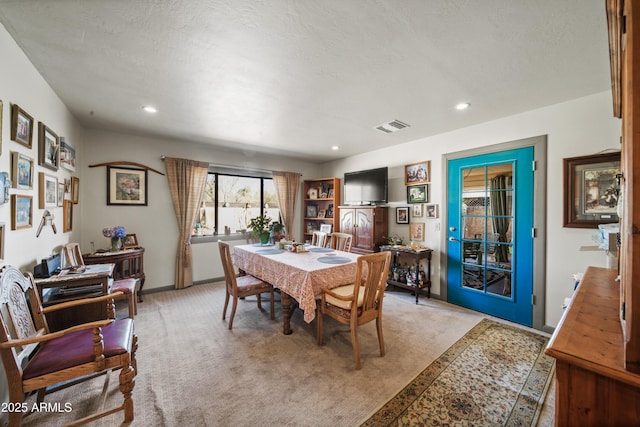 carpeted dining room with a textured ceiling