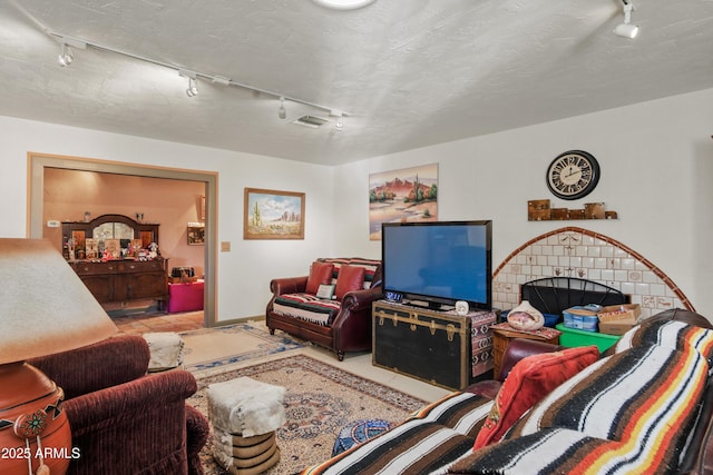 tiled living room featuring rail lighting and a textured ceiling