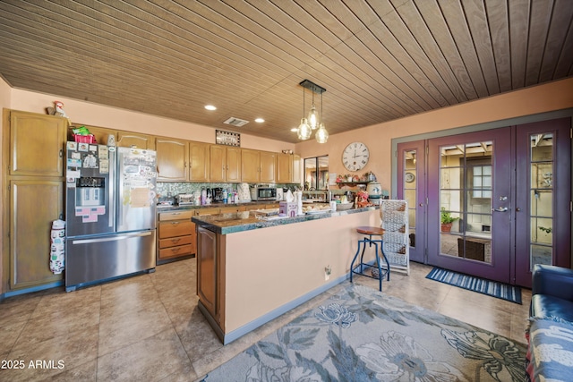 kitchen featuring backsplash, stainless steel appliances, decorative light fixtures, a notable chandelier, and a kitchen island