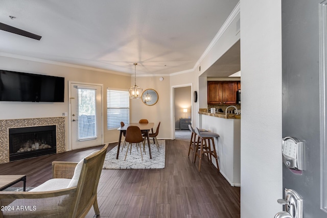 dining space with crown molding, a tile fireplace, and a chandelier