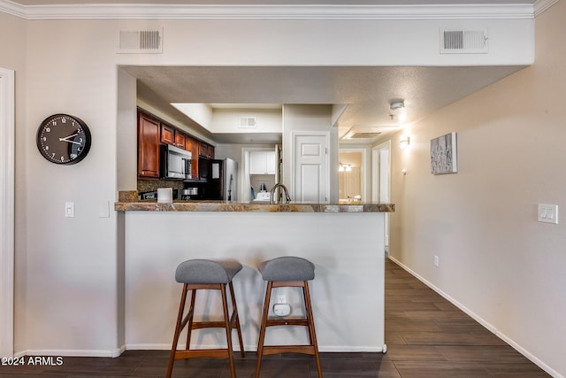 kitchen with kitchen peninsula, a kitchen breakfast bar, black refrigerator, crown molding, and sink