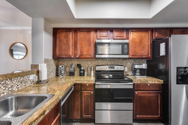 kitchen with appliances with stainless steel finishes, backsplash, a tray ceiling, crown molding, and sink