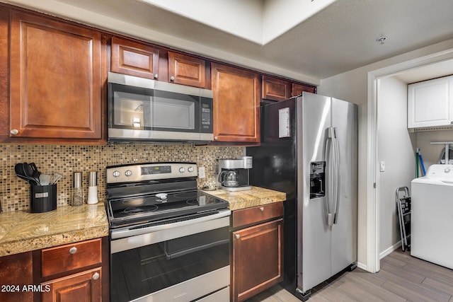 kitchen with decorative backsplash, appliances with stainless steel finishes, light wood-type flooring, and washer / clothes dryer