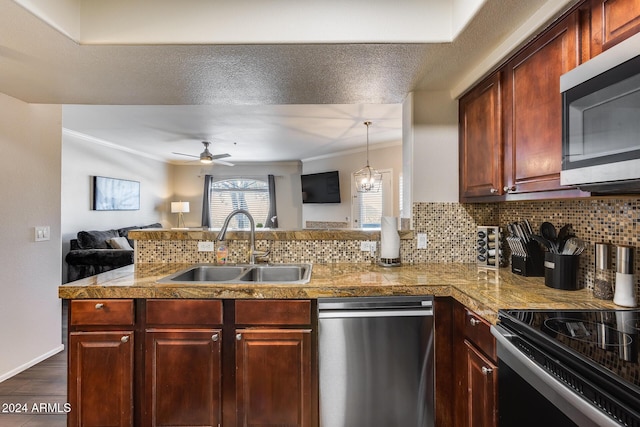 kitchen with decorative backsplash, appliances with stainless steel finishes, kitchen peninsula, ceiling fan with notable chandelier, and sink