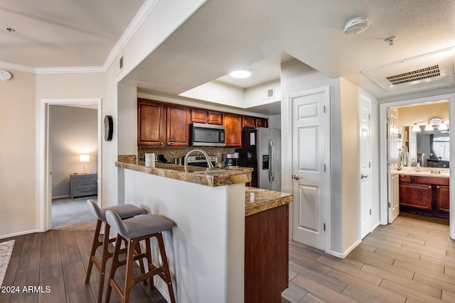 kitchen featuring stainless steel appliances, tasteful backsplash, a kitchen breakfast bar, kitchen peninsula, and crown molding