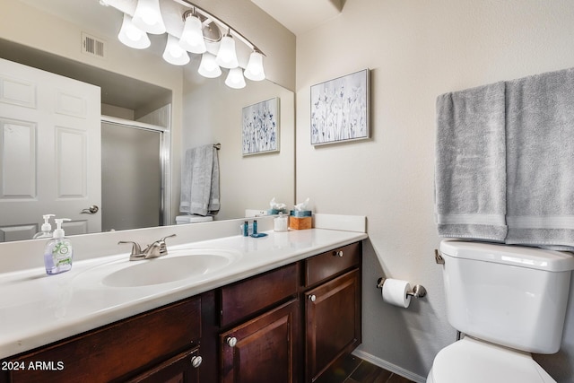 bathroom featuring vanity, toilet, and a shower with door