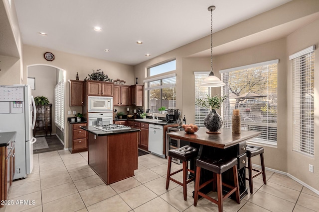 kitchen with white appliances, decorative light fixtures, a center island, and light tile patterned floors