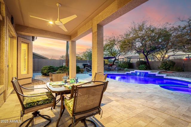 pool at dusk featuring a patio, an in ground hot tub, and ceiling fan