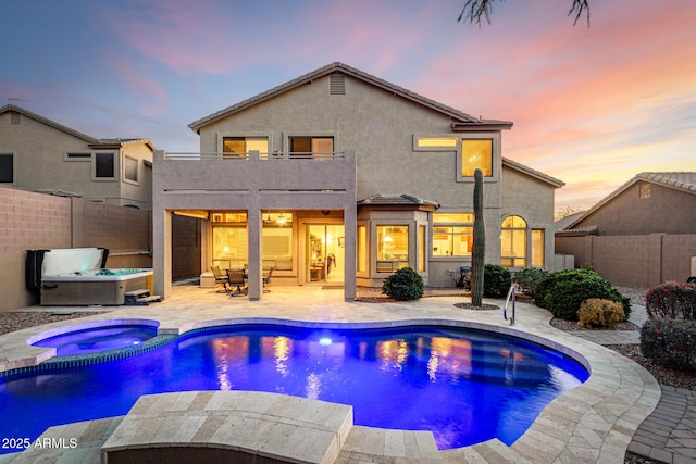 pool at dusk featuring a patio area and an in ground hot tub