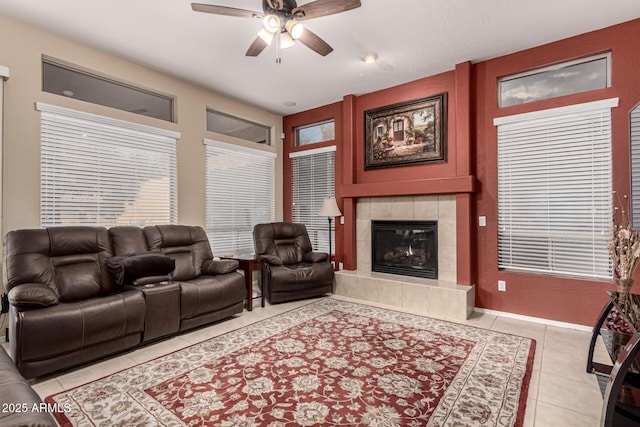 tiled living room with a tile fireplace and ceiling fan