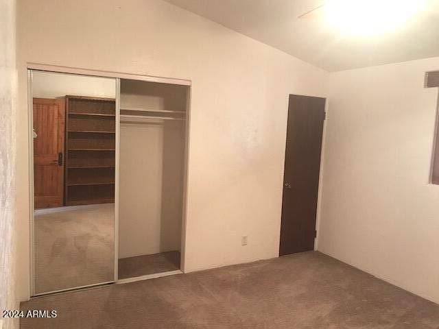 unfurnished bedroom with a closet and dark carpet