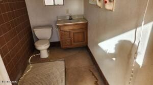 bathroom featuring vanity, toilet, and brick wall