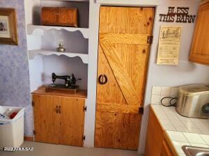 kitchen with a barn door and tile countertops