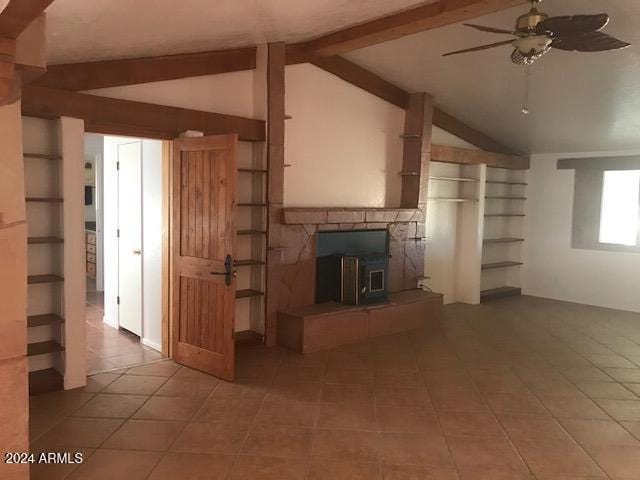 unfurnished living room featuring tile patterned flooring, vaulted ceiling with beams, a wood stove, and ceiling fan