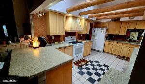 kitchen with kitchen peninsula, white appliances, and ventilation hood