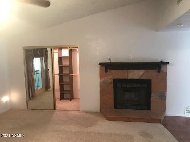 unfurnished living room featuring a fireplace, carpet, and lofted ceiling