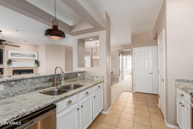 kitchen featuring decorative light fixtures, white cabinets, light carpet, sink, and a tile fireplace