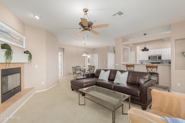 living room with ceiling fan, a fireplace, and light carpet