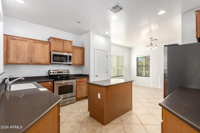 kitchen featuring an inviting chandelier, sink, decorative light fixtures, a kitchen island, and stainless steel appliances