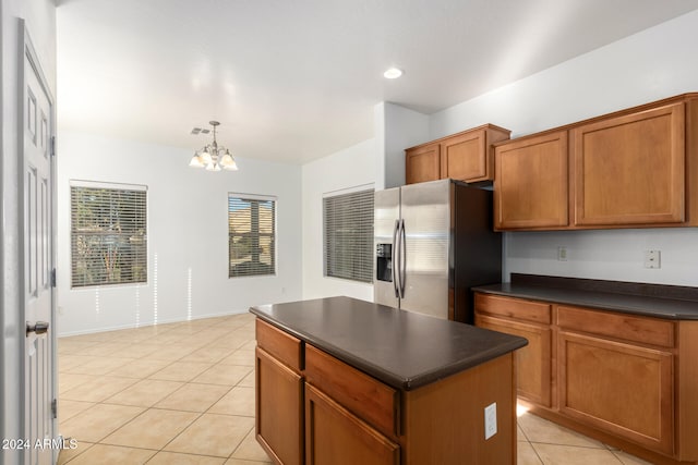 kitchen featuring stainless steel refrigerator with ice dispenser, light tile patterned floors, a chandelier, a kitchen island, and hanging light fixtures