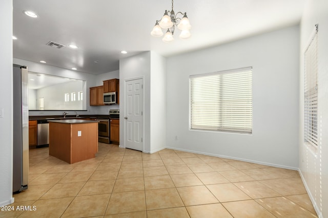 kitchen featuring pendant lighting, a center island, appliances with stainless steel finishes, a notable chandelier, and light tile patterned flooring