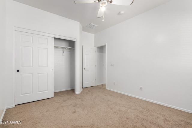 unfurnished bedroom featuring ceiling fan, light colored carpet, and a closet