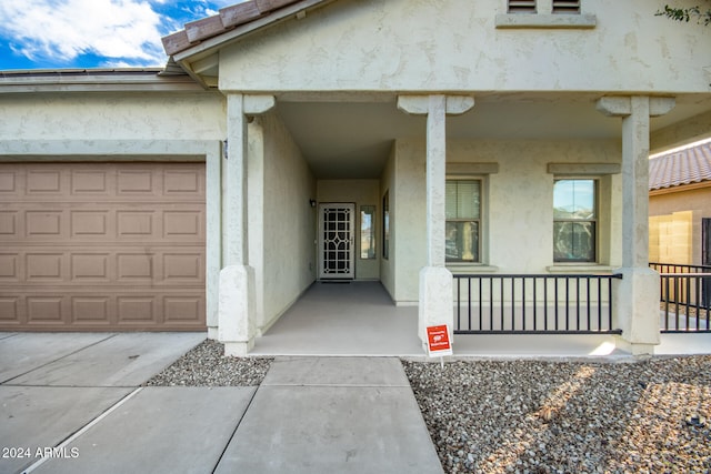 doorway to property featuring covered porch and a garage