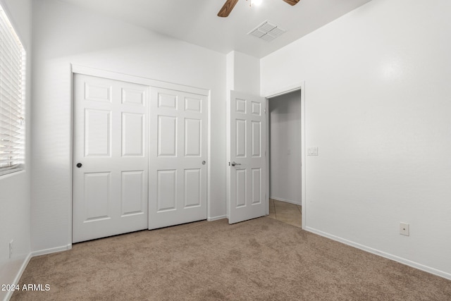 unfurnished bedroom with a closet, light colored carpet, and ceiling fan