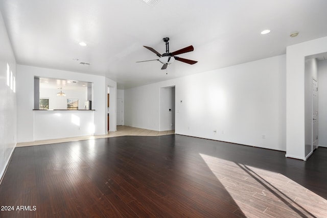 unfurnished living room featuring ceiling fan with notable chandelier and dark hardwood / wood-style flooring