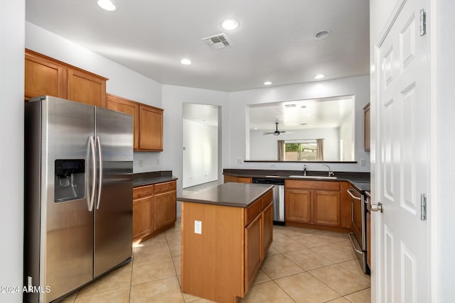 kitchen with appliances with stainless steel finishes, ceiling fan, sink, light tile patterned floors, and a center island