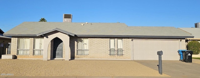 view of front facade with brick siding, driveway, a chimney, and an attached garage