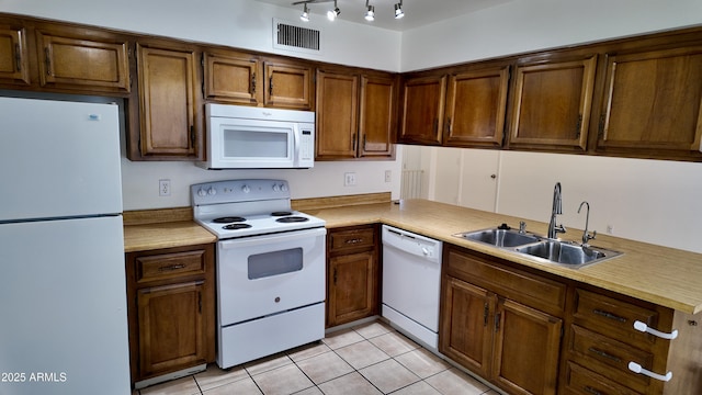 kitchen featuring light tile patterned flooring, white appliances, a sink, visible vents, and light countertops