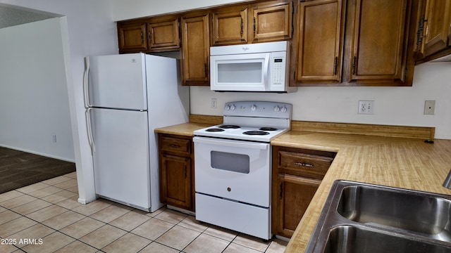 kitchen featuring white appliances, light countertops, a sink, and light tile patterned floors