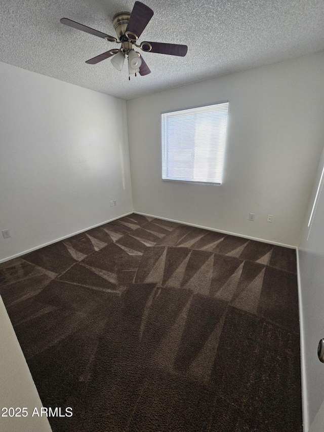 spare room featuring a textured ceiling, dark colored carpet, and ceiling fan